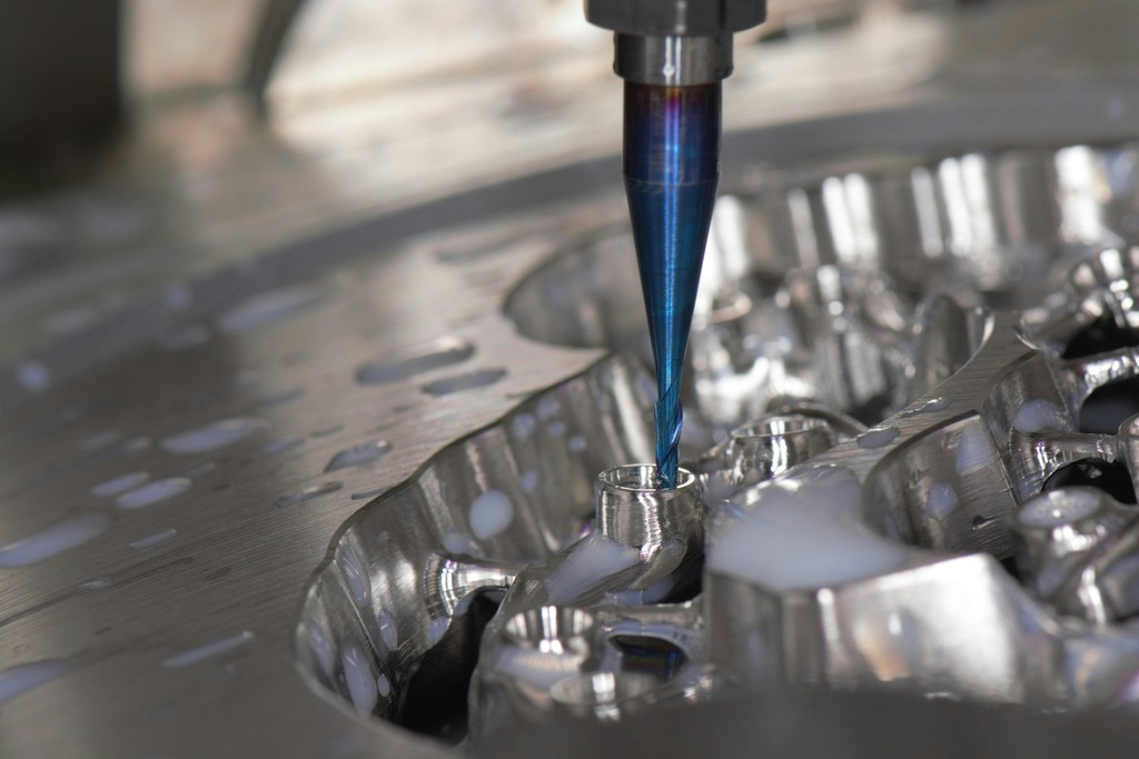 A milling bur cutting restorations from a metal disc under coolant.